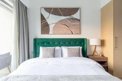 a bedroom with a bed with a green headboard at Spacious 2BR with Burj Khalifa View in Downtown Dubai in Dubai