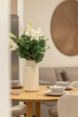 a white vase with white flowers on a table at Spacious 2BR with Burj Khalifa View in Downtown Dubai in Dubai