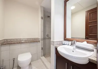 a bathroom with a sink and a toilet and a mirror at Cozy 2 Br Heart of Palm Jumeirah in Dubai