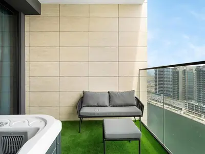 a bathroom with a tub and a chair on a balcony at Modern Studio with Jacuzzi and Premium Amenities in Dubai