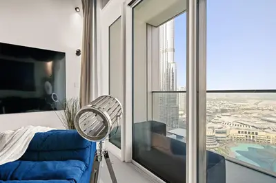 a room with a blue chair and a window at Luxury Apartments at Grande with Burj Khalifa & Fountain View Walk to Dubai Mall, Private Cinema in Dubai