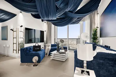 a living room with blue furniture and a large window at Luxury Apartments at Grande with Burj Khalifa & Fountain View Walk to Dubai Mall, Private Cinema in Dubai