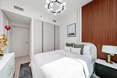a bedroom with a white bed and a chandelier at Homey 1BR apartment in Creek Harbour in Dubai