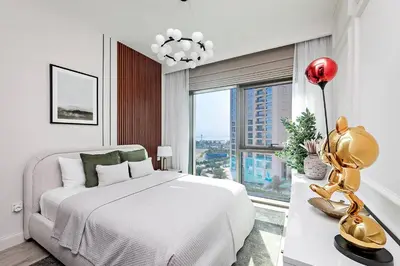 a white bedroom with a large bed and a large window at Homey 1BR apartment in Creek Harbour in Dubai