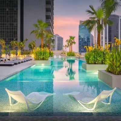 a swimming pool with two chairs and a building at Smart Studio in Business Bay Near Burj Khalifa in Dubai