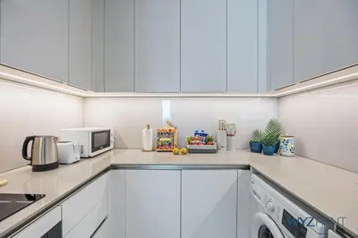 a kitchen with white cabinets and a microwave at Deluxe 1 BR in The Address JBR Beachfront Access in Dubai