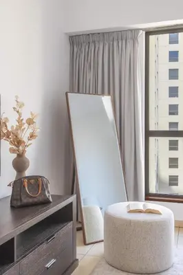 a room with a ottoman and a mirror and a table at Frank Porter - Sadaf 7, JBR in Dubai