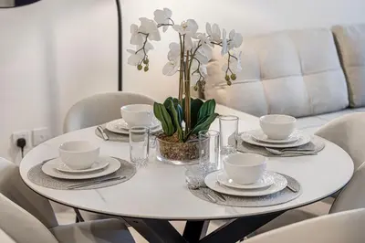 a white table with plates and cups and a plant at Marina Horizon by LIV High Floor 1BR, For 5 Guests, Dual Gyms & Marina View in Dubai
