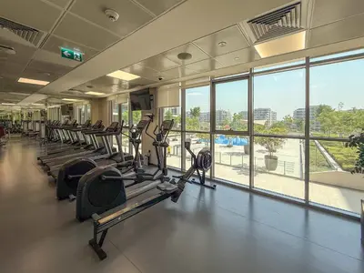 a gym with rows of treadmills and a large window at Frank Porter - Acacia, Park Heights Tower A in Dubai