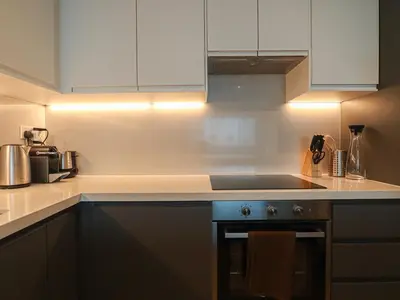 a kitchen with white cabinets and a stove top oven at HiGuests - 2 BR Escape Golf View Haven in The Greens in Dubai