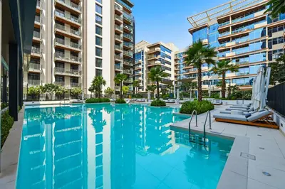 a swimming pool with palm trees and buildings at New Cozy Studio, Ideal for 2 in Kensington Waters in Dubai