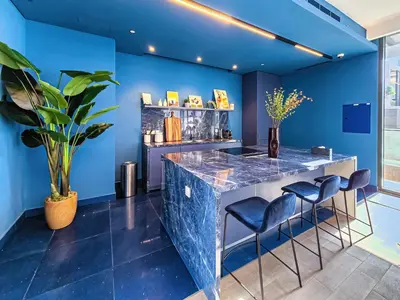 a blue room with a bar with blue walls and stools at New Cozy Studio, Ideal for 2 in Kensington Waters in Dubai