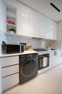 a kitchen with white cabinets and a washer and oven at Epic Pool I JVC Studio I Fully Furnished in Dubai