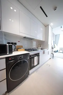 a kitchen with white cabinets and a dishwasher at Epic Pool I JVC Studio I Fully Furnished in Dubai