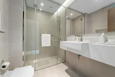 a bathroom with a glass shower and a sink at Parkside 2BR plus Maid Canal Front in Dubai