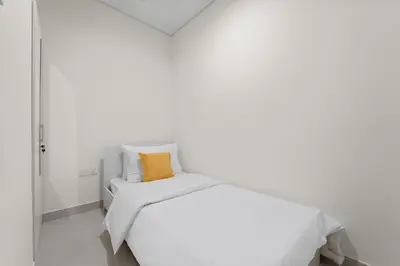 a white bedroom with a white bed with an orange pillow at Parkside 2BR plus Maid Canal Front in Dubai