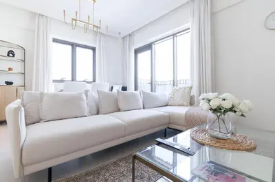 a white living room with a white couch and a glass table at StayShort - Dubai Creek Harbour sleeps 6 in a Great Location in Dubai