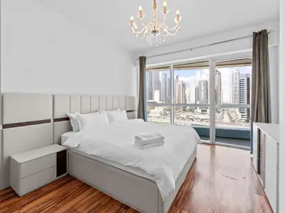 a bedroom with a white bed and a large window at 1BR in JLT, Steps from Metro, Marina & Mall in Dubai