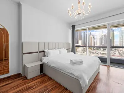 a bedroom with a large white bed and a chandelier at 1BR in JLT, Steps from Metro, Marina & Mall in Dubai