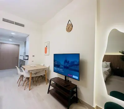 a living room with a television and a table with chairs at Mahenti – Elegant Studio Apartment | Azizi Riviera in Dubai