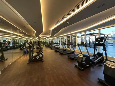 a gym with a row of treadmills and machines at Mahenti - Bright studio near Miracle Garden in Dubai