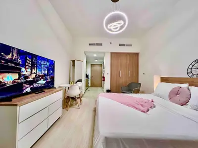 a bedroom with a large bed and a flat screen tv at Mahenti - Contemporary Studio Living in Meydan in Dubai