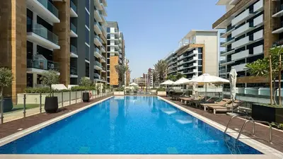 a large blue swimming pool with chairs and buildings at Mahenti- Chic 1BR with Burj & Downtown View in Dubai