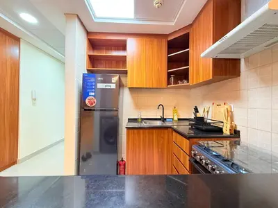 a kitchen with wooden cabinets and a stainless steel refrigerator at Mahenti - Bright & Cozy Studio Metro Accessible in Dubai