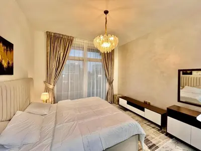 a bedroom with a large bed and a chandelier at Mahenti - Jewelz · With balcony easy to pool & gym in Dubai