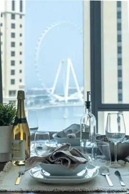 a table with plates and wine bottles and glasses at Frank Porter - Aurora Tower, Dubai Marina in Dubai