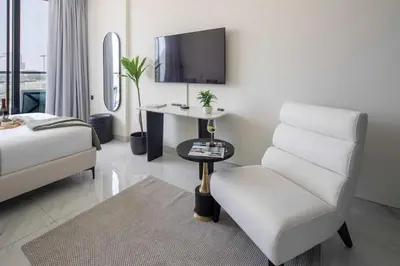 a living room with a chair and a tv at Frank Porter - Samana Golf Avenue in Dubai