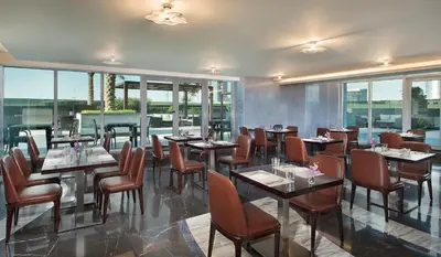 a restaurant with tables and chairs and windows at Atana Hotel in Dubai