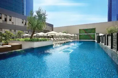 a swimming pool with chairs and umbrellas on a building at DAMAC Maison Cour Jardin - Pool & Gym - Free Parking in Dubai
