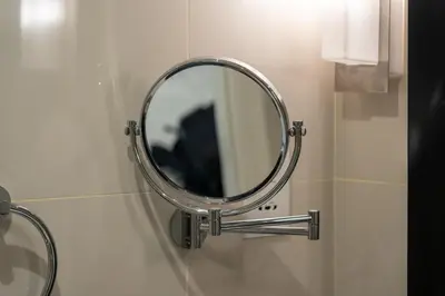 a round mirror on a wall in a bathroom at DAMAC Maison Cour Jardin - Pool & Gym - Free Parking in Dubai