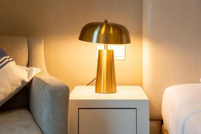 a gold lamp on a table next to a bed at DAMAC Maison Cour Jardin - Pool & Gym - Free Parking in Dubai
