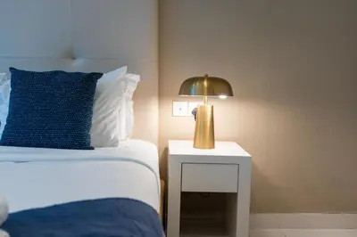 a bedroom with a bed and a lamp on a side table at DAMAC Maison Cour Jardin - Pool & Gym - Free Parking in Dubai