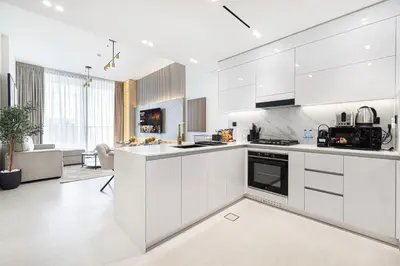 a white kitchen with white cabinets and appliances at Deluxe Binghatti JVC Suites by Hostiva - City View in Dubai