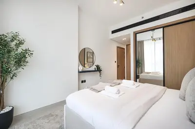 a white bedroom with two beds and a mirror at Deluxe Binghatti JVC Suites by Hostiva - City View in Dubai