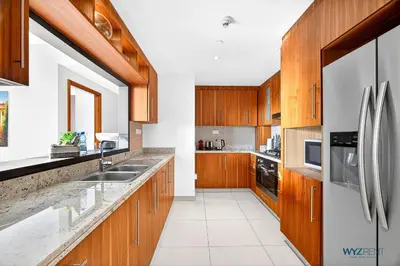 a kitchen with wooden cabinets and stainless steel appliances at Iconic 4BR with Burj & Fountain Views Boulevard Point in Dubai