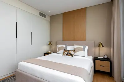 a bedroom with a large white bed with two lamps at Maison Privee - Chic Downtown Living with Dubai Cityscape Views in Dubai