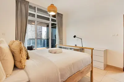 a white bedroom with a bed and a window at Modern 2 Bed with Waterfront Views, Gym & Pool in Dubai
