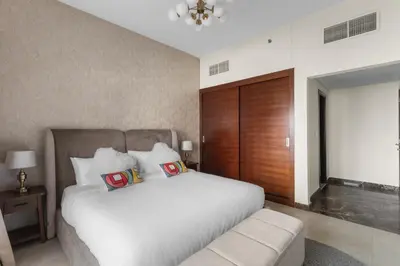 a bedroom with a white bed and a wooden door at Stylish 1-Bedroom with Balcony & Amenities in Marina in Dubai