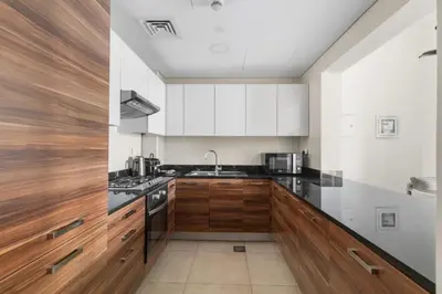 a kitchen with white cabinets and black counter tops at Stylish 1-Bedroom with Balcony & Amenities in Marina in Dubai