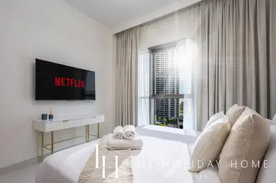a white bedroom with a bed and a tv at LUX The Creekside Skyline View Suite in Dubai