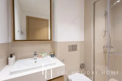 a bathroom with a sink and a shower with a mirror at LUX The Creekside Skyline View Suite in Dubai
