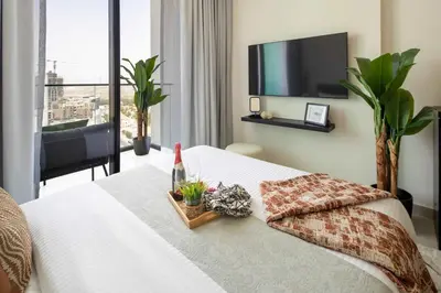 a bedroom with a bed with a tv on the wall at Frank Porter - Binghatti Azure in Dubai