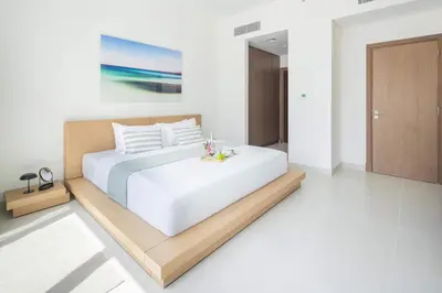a bedroom with a white bed with a wooden frame at Frank Porter - Canal Front Residence 9A in Dubai