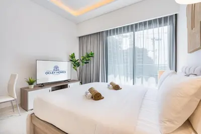 a white bedroom with a bed and a television at Elegant & Cozy Home with Stylish Modern Interiors in Dubai