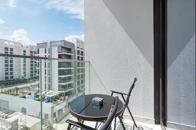 a table and chair on a balcony with a view of a city at Elegant & Cozy Home with Stylish Modern Interiors in Dubai