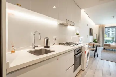 a white kitchen with a sink and a stove at FIRST CLASS Studio Modern Elegance in Dubai